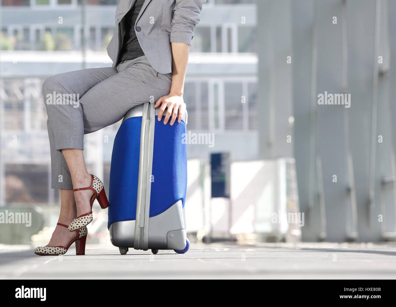 Taille en bas business woman sitting on suitcase at airport Banque D'Images