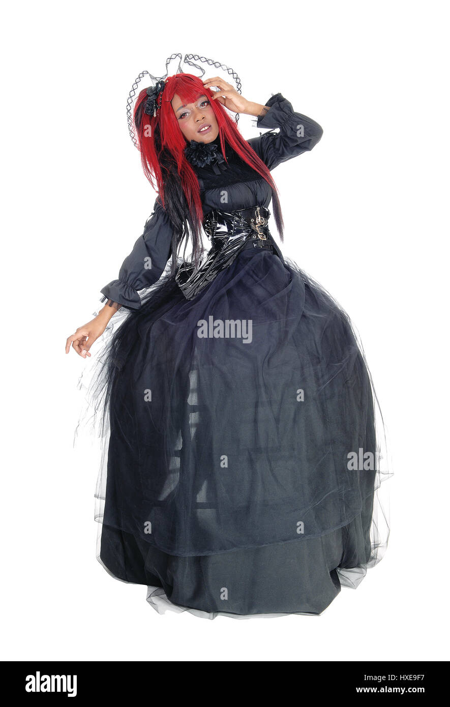Une belle jeune femme africaine debout dans une longue robe noire et rouge victorien cheveux, isolée pour fond blanc. Banque D'Images