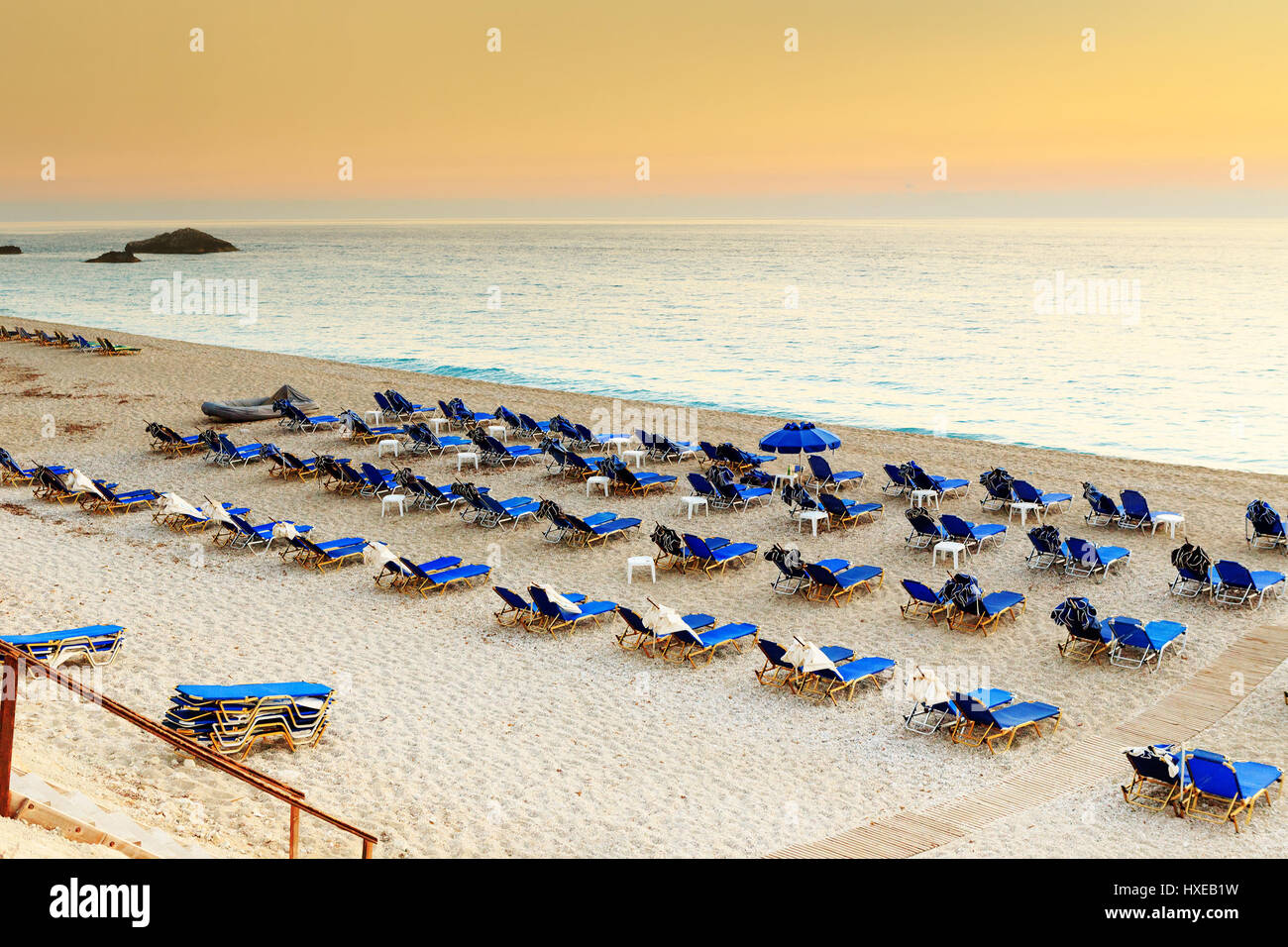 Chaises et parasols sur beach resort en Grèce, au coucher du soleil Banque D'Images