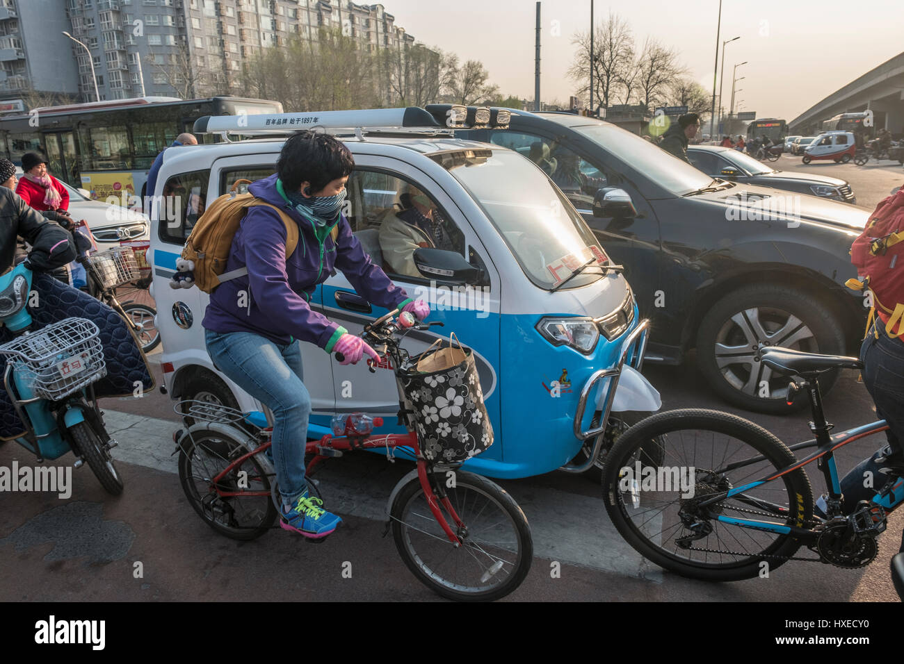 Bicyclettes, mini voiture électrique sans permis et de voitures à essence sont sur la route ensemble, à Beijing, en Chine. 28-Mar-2017 Banque D'Images