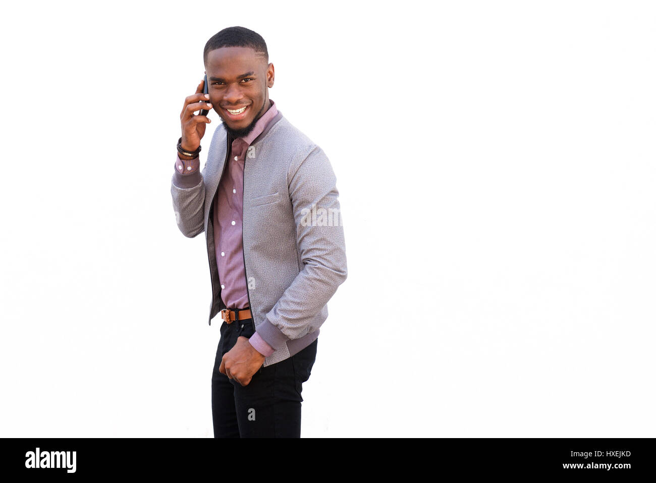 Portrait d'un jeune mec talking on mobile phone against white background Banque D'Images