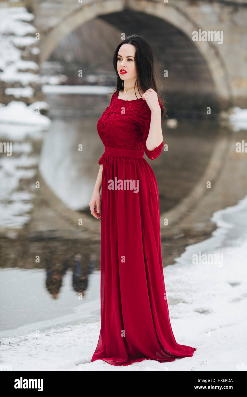 Femme en robe rouge debout dans la neige Banque D'Images