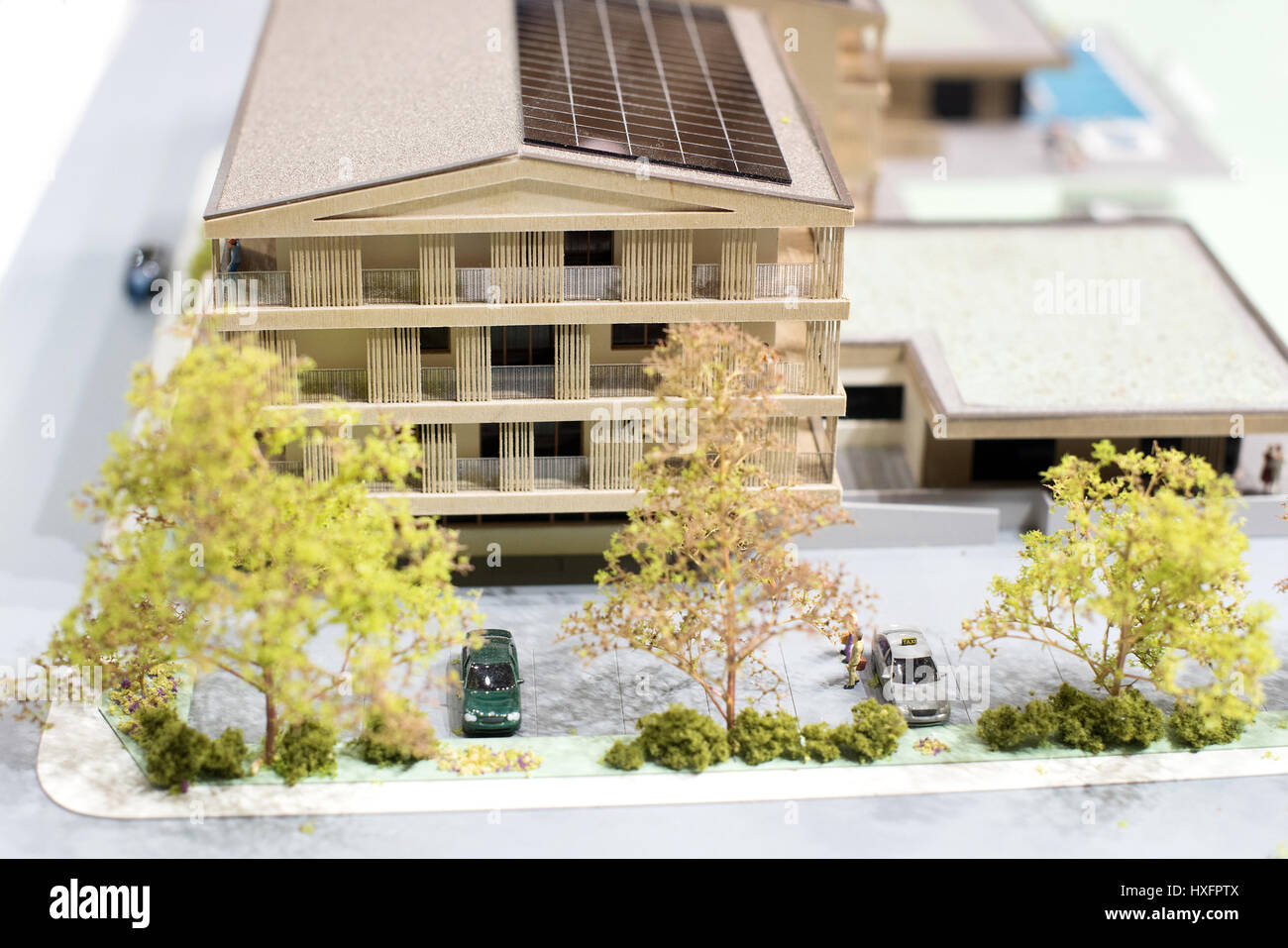 Modèle à l'échelle d'un éco-friendly chambre ou petit bloc d'appartement avec un grand garage et des panneaux solaires sur le toit derrière les arbres Banque D'Images