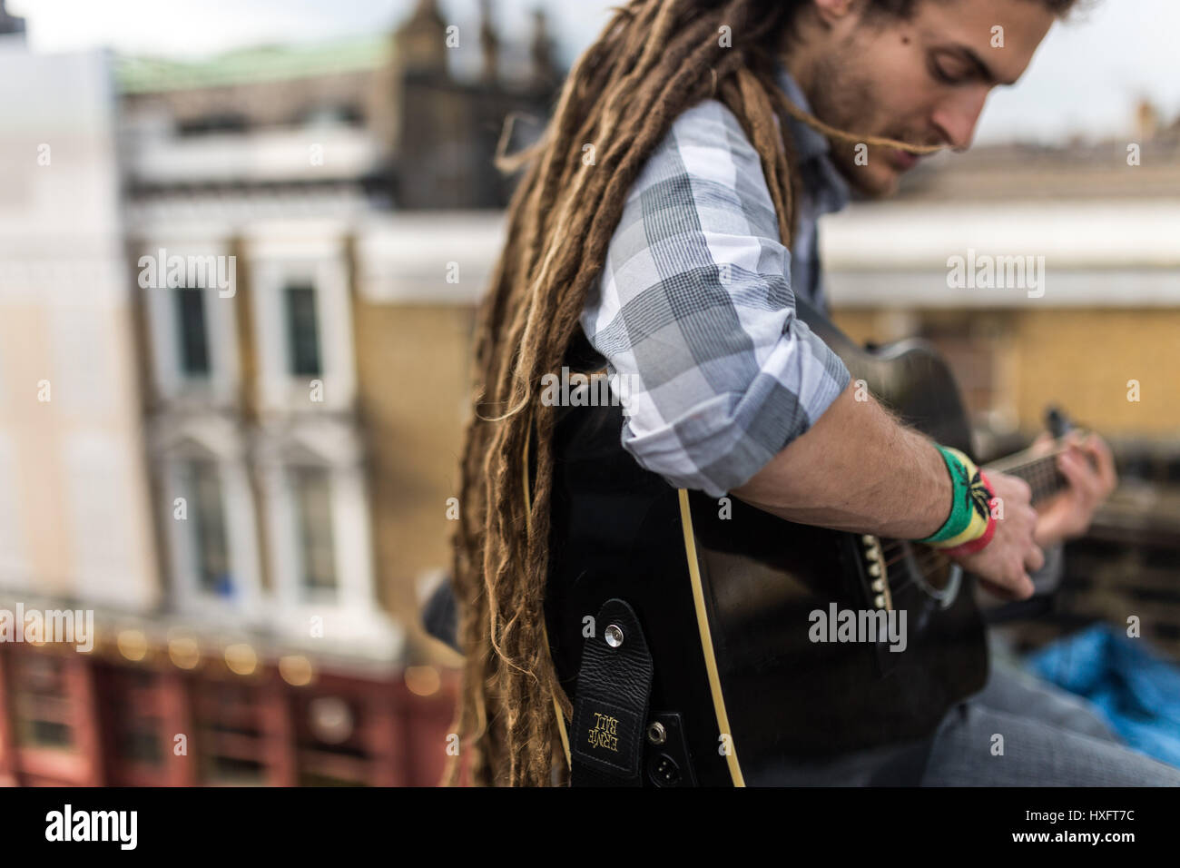 Rasta est un musicien jouant de la guitare sur le toit d'un squat dans le quartier de Camden Banque D'Images