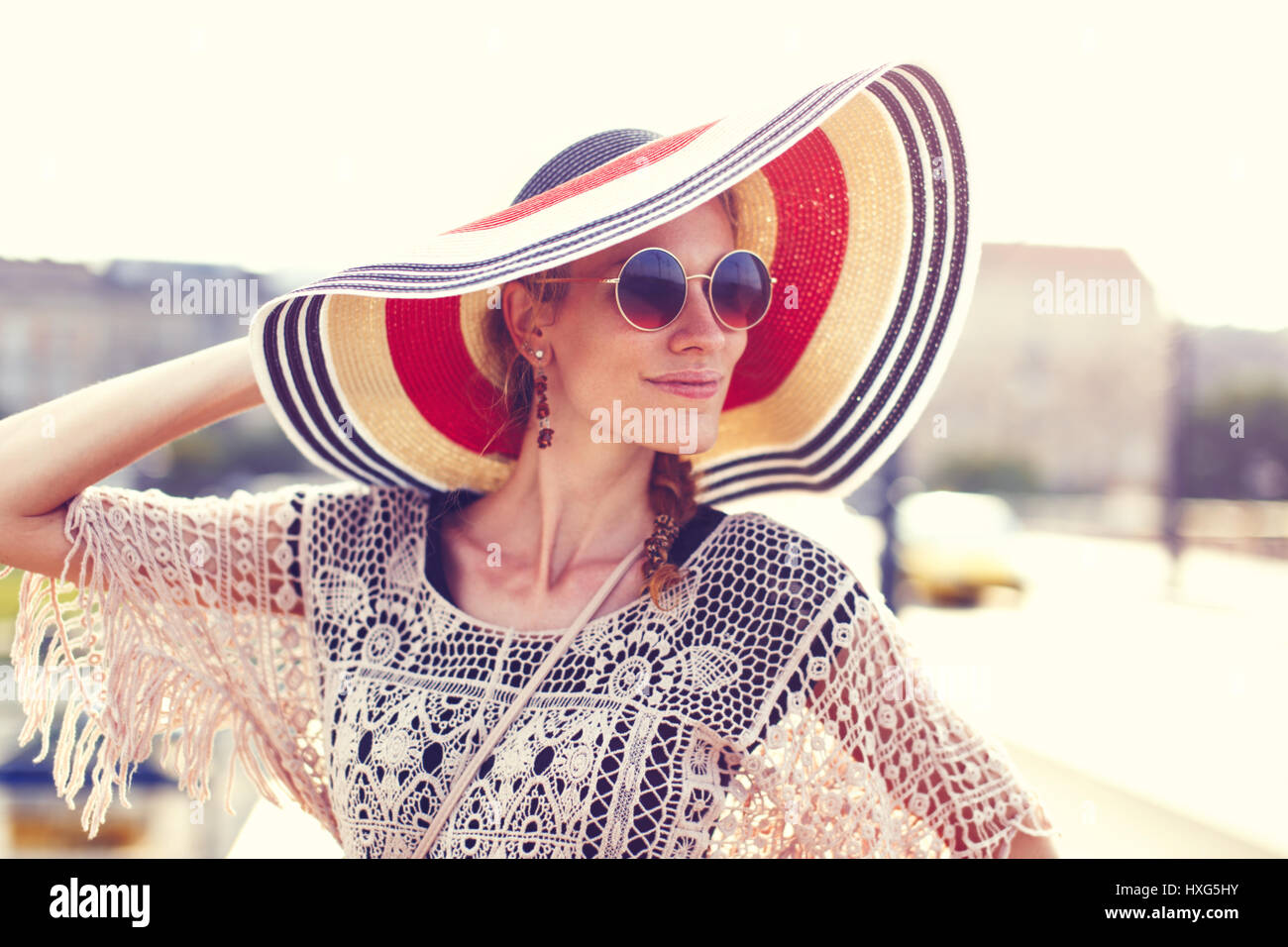 Happy young woman holding touristique hat outdoor, looking away Banque D'Images