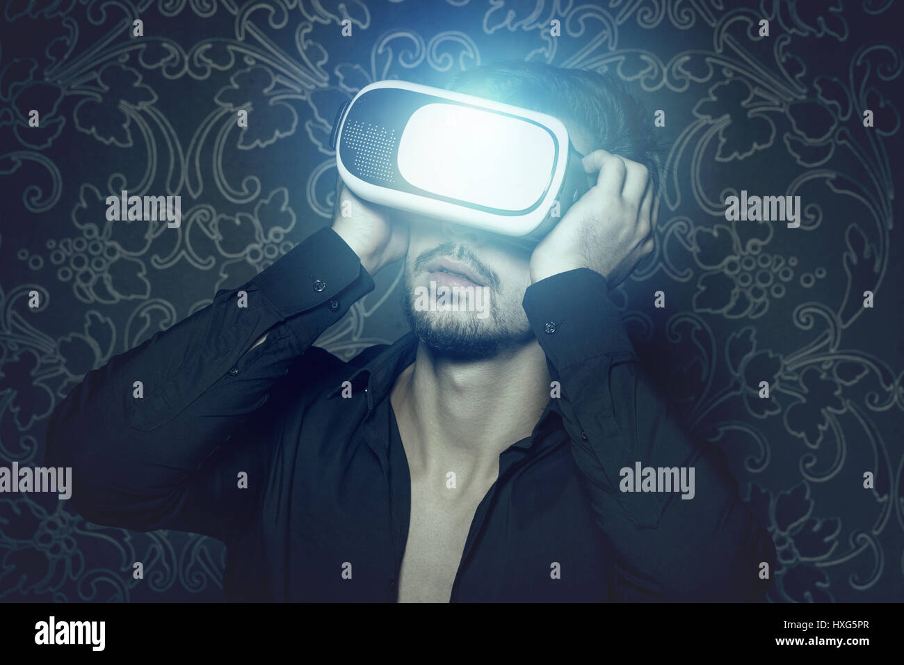 Young caucasian man in casque de réalité virtuelle, de simulation en profitant de style cinématographique et de la lumière Banque D'Images