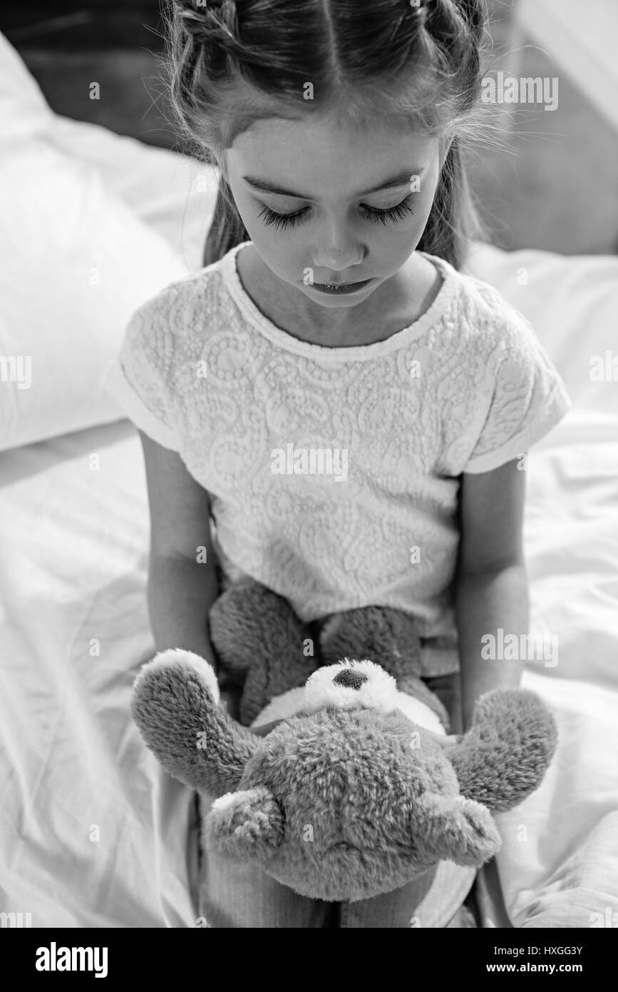 Photo en noir et blanc de upset girl avec ours en peluche dans la chambre de l'hôpital Banque D'Images