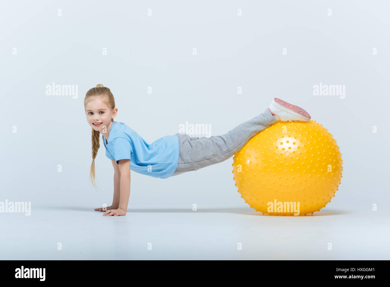 Smiling fille sportive l'entraînement avec fitness ball on white Banque D'Images