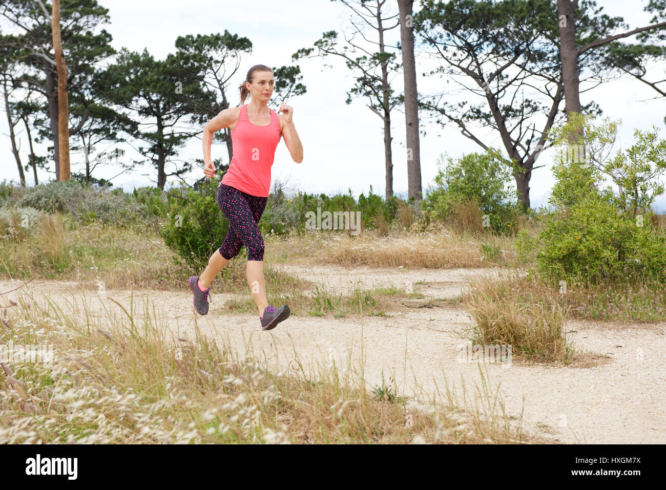 Portrait de femme sur le sentier de jogging à l'extérieur avec les deux pieds du sol Banque D'Images