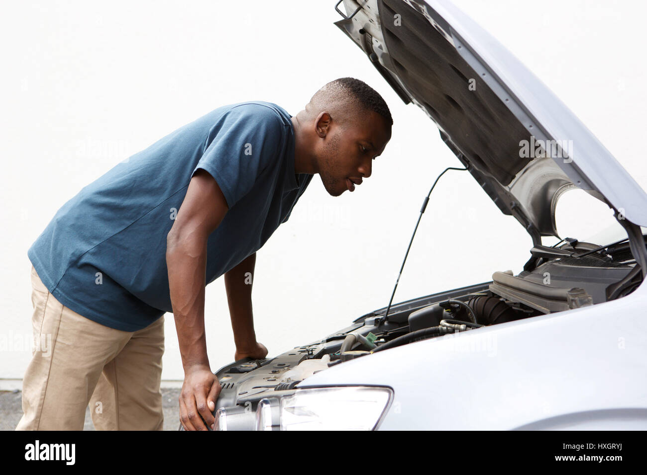 Side portrait of young african american guy à sous le capot de voiture en panne Banque D'Images