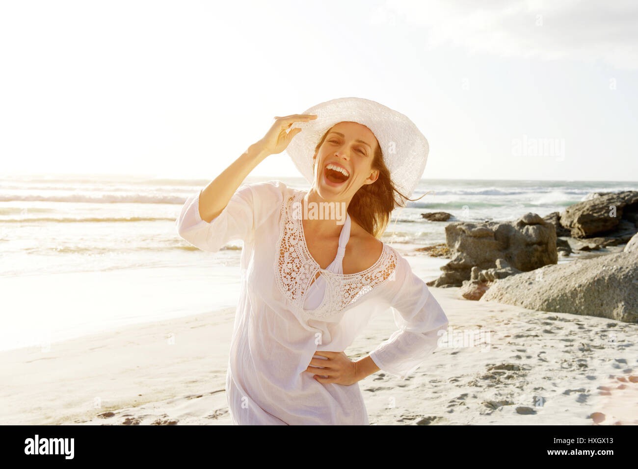 Portrait d'une belle femme insouciante marchant sur la plage avec robe et chapeau Banque D'Images