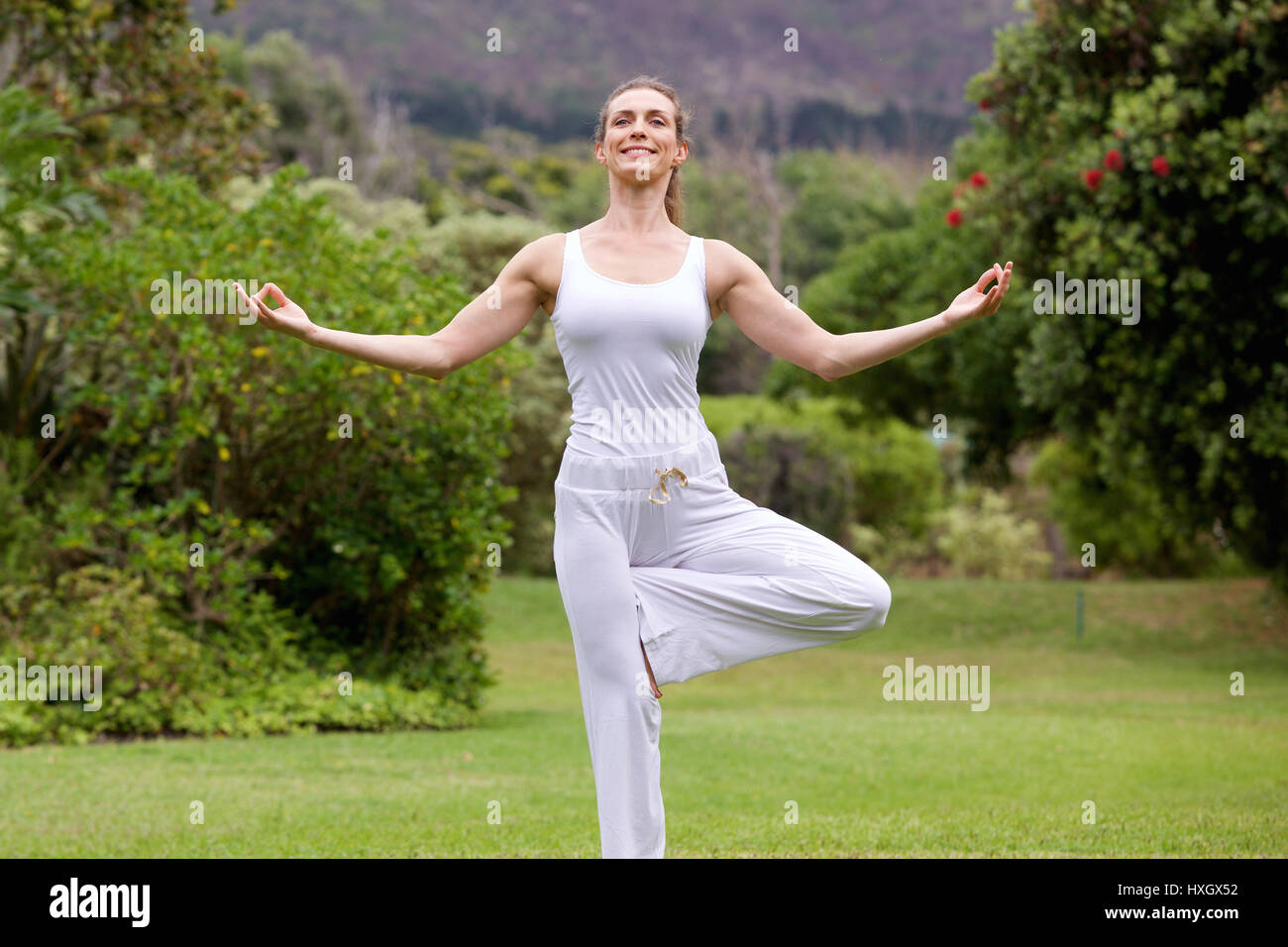 Portrait of a smiling woman yoga debout sur une jambe dans park Banque D'Images