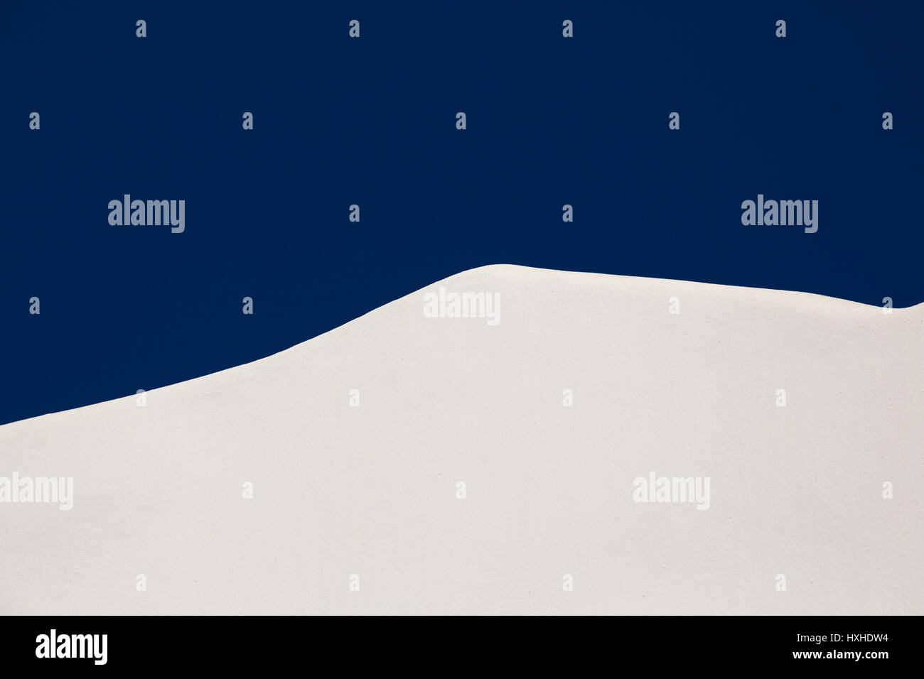 Résumé Contexte architectural avec un angle d'un mur blanchi à la chaux sur une villa grecque contre un fond bleu ciel ensoleillé Banque D'Images