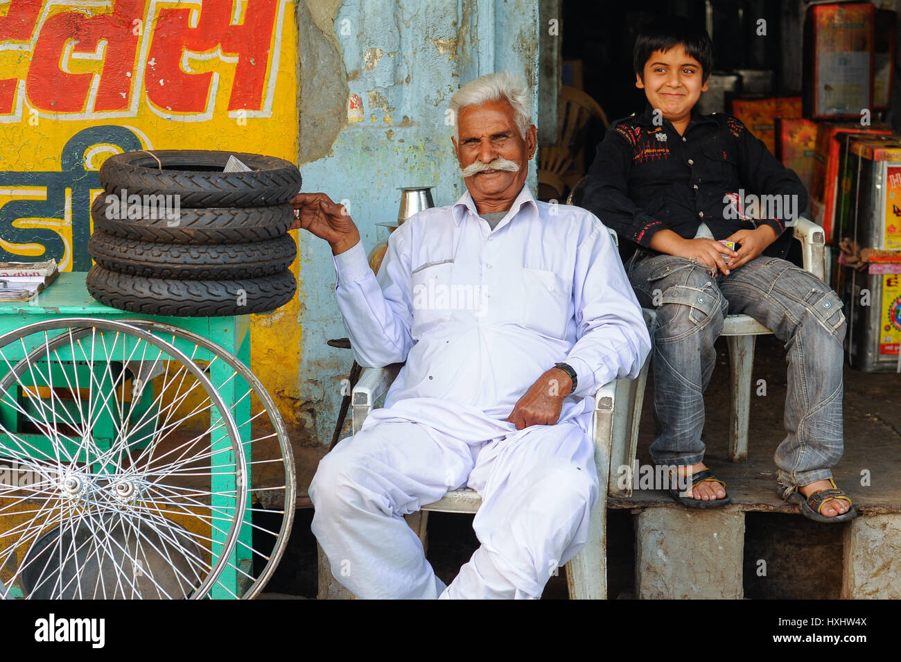 Un vieil homme et son petit-fils s'asseoir fièrement à l'extérieur de leur magasin de vélos à Udaipur Banque D'Images