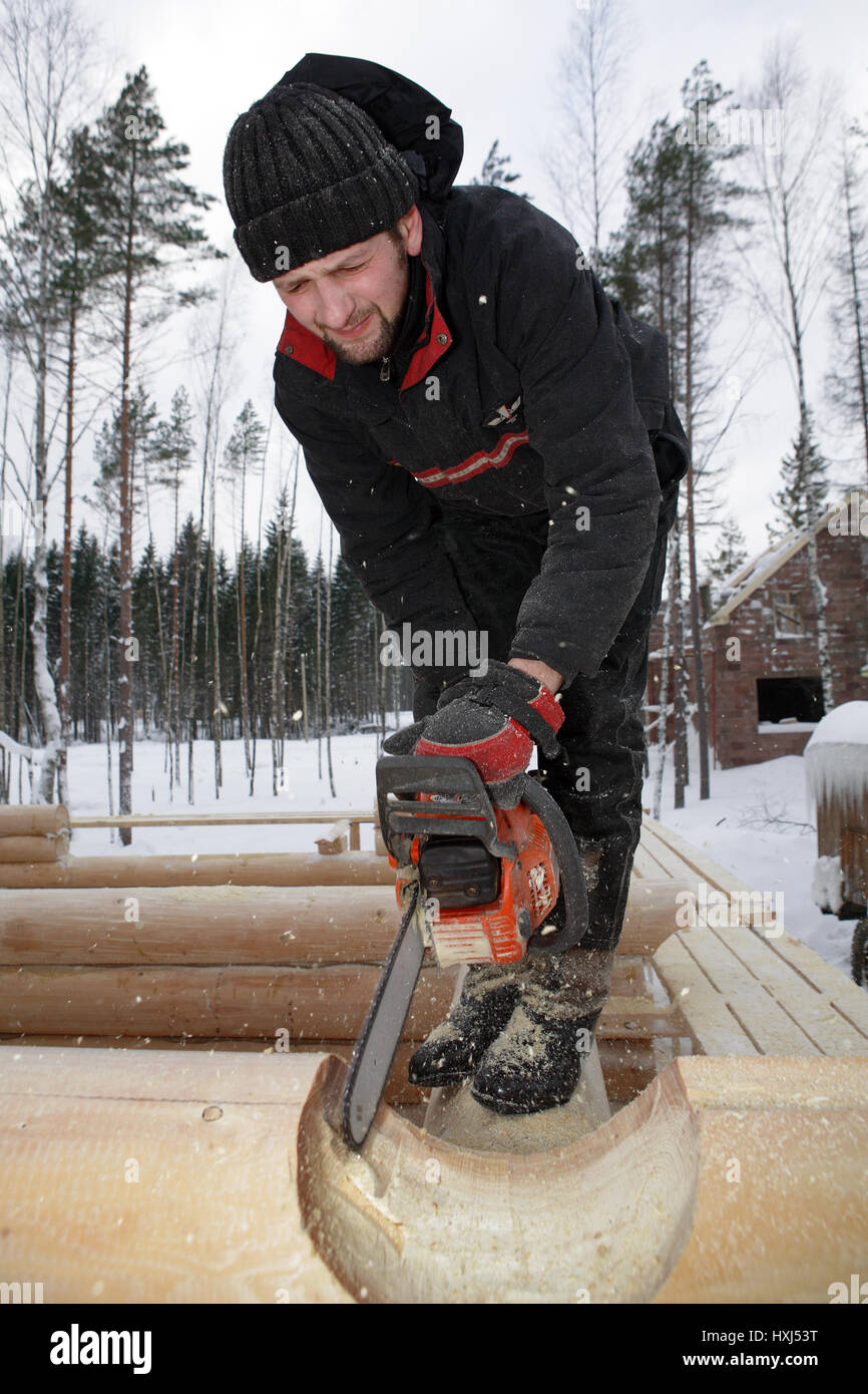 Leningrad Region, Russie - Février 2, 2010 : Builder gère à l'aide de tronçonneuse, il journal découper l'encoche selle ronde. Banque D'Images