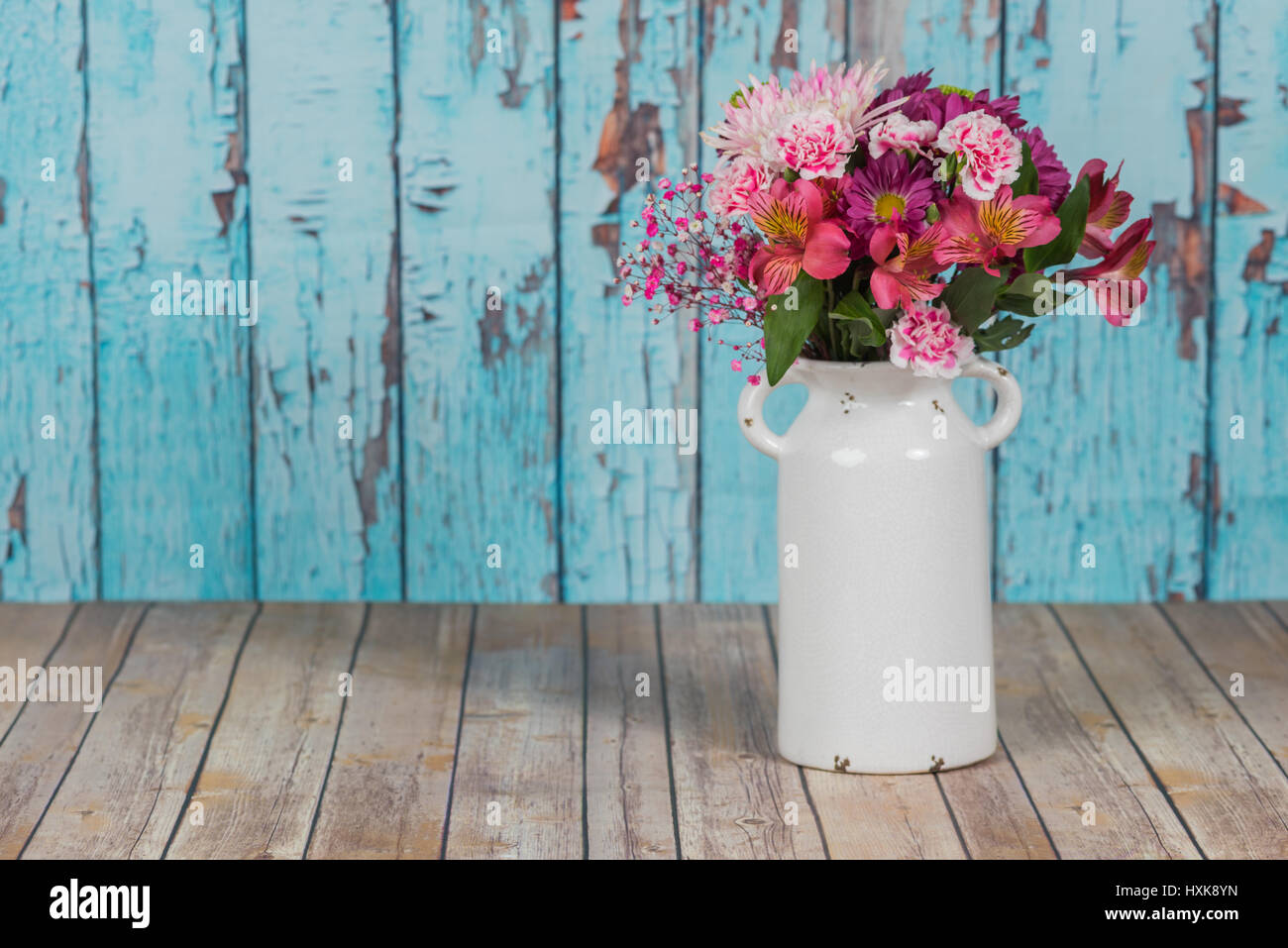Fleurs dans un vase blanc vintage avec arrière-plan de la peinture craquelée Banque D'Images