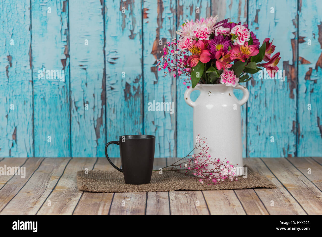 Vintage vase blanc avec des fleurs et une tasse avec un fond de peinture pelée Banque D'Images