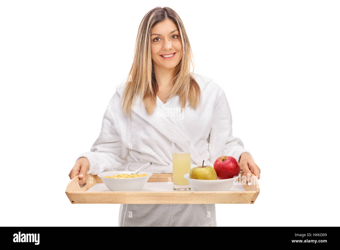 Jolie jeune femme portant un peignoir et tenant un plateau de petit-déjeuner isolé sur fond blanc Banque D'Images