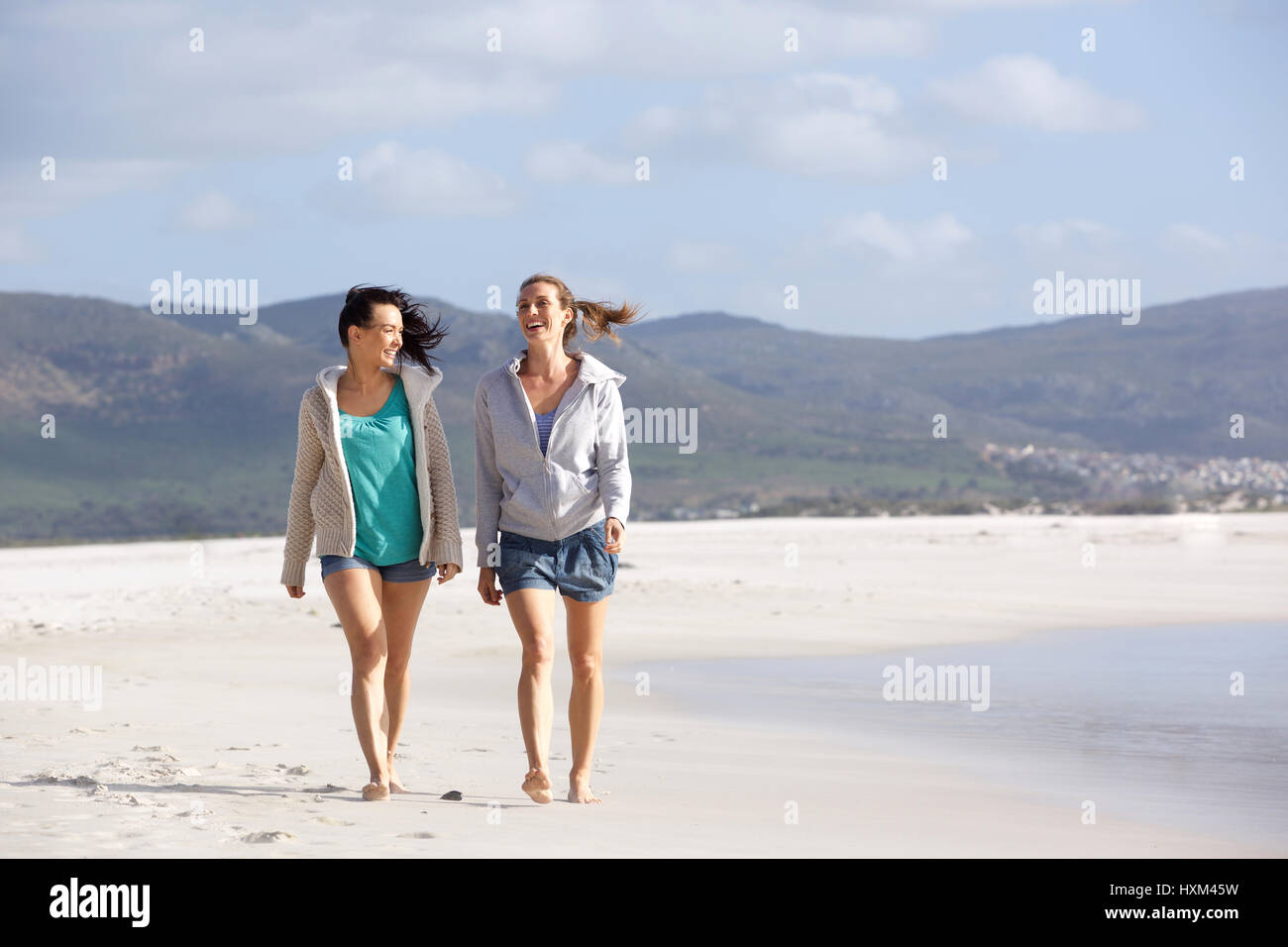 Portrait de deux amies marchant et parlant sur la plage Banque D'Images