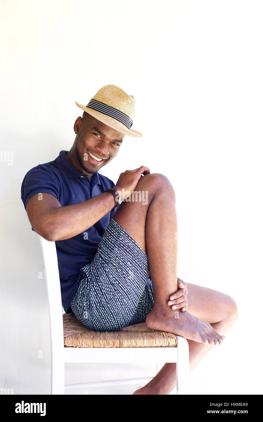 Portrait de jeune homme élégant assis sur une chaise et smiling against white background Banque D'Images