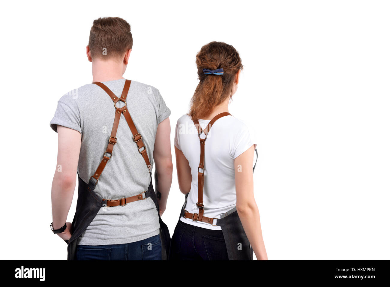 Jeunes chefs ou maîtres d'homme et de la femme pose, portant des tabliers isolé sur fond blanc. Banque D'Images