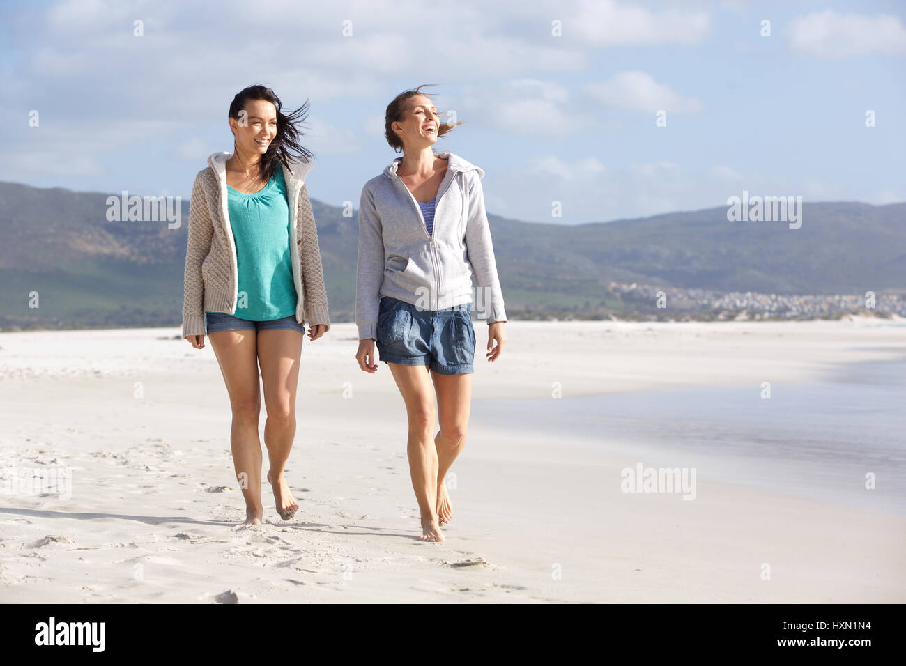 Portrait of two smiling women friends walking on beach ensemble Banque D'Images