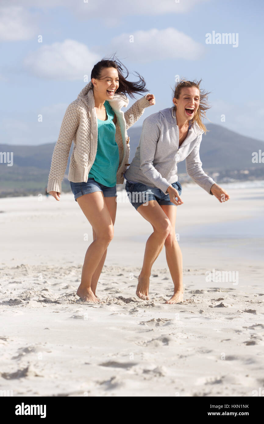 Portrait de deux amies rire aux pieds nus sur la plage Banque D'Images