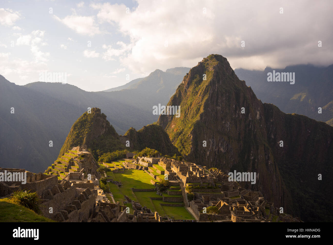 Machu Picchu partiellement éclairée par la dernière lumière du soleil. Vue grand angle de la terrasse avec vue panoramique et ciel Sentier lumineux au premier plan. Banque D'Images