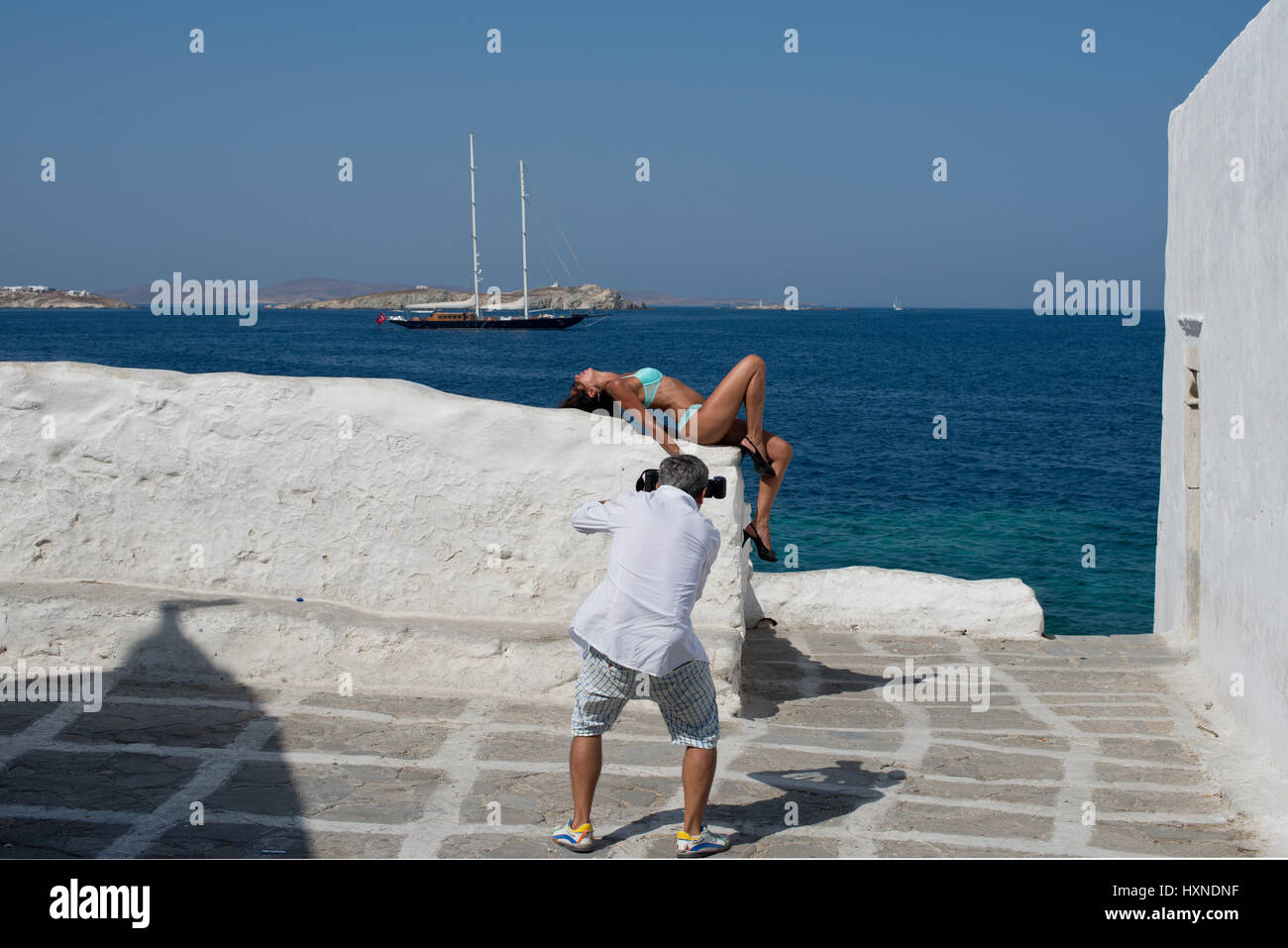 Des photos d'un photographe woman in bikini sur mur blanchi près de waterfront, dans la ville de Mykonos, Grèce Banque D'Images