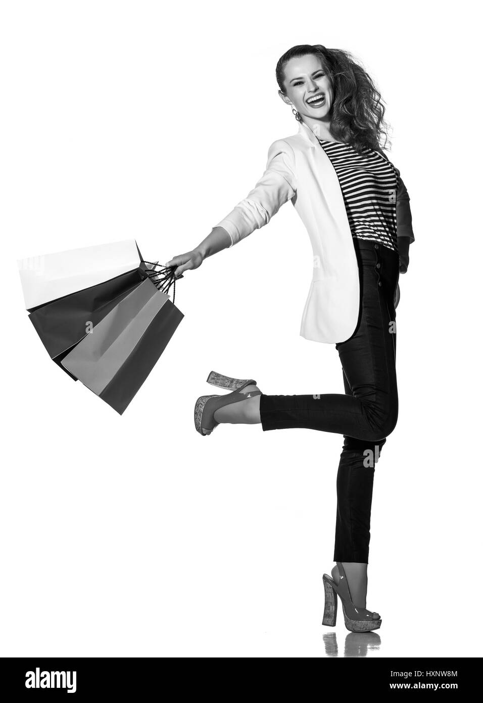 Le Shopping. L'approche française. Full Length portrait of smiling young woman with shopping bags posant sur fond blanc Banque D'Images