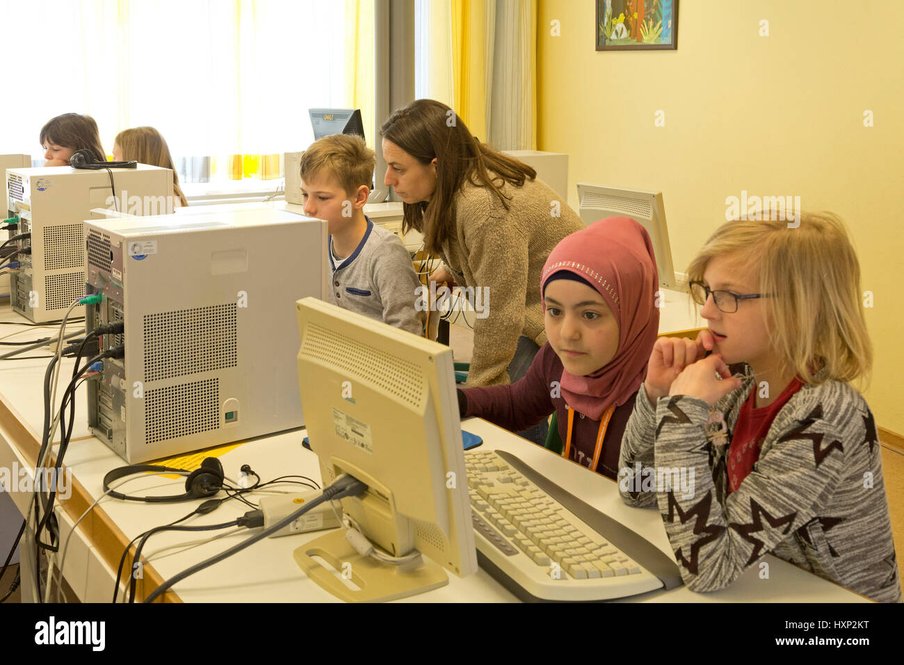 Les enfants d'école primaire en travaillant avec un ordinateur, leur professeur de les aider Banque D'Images