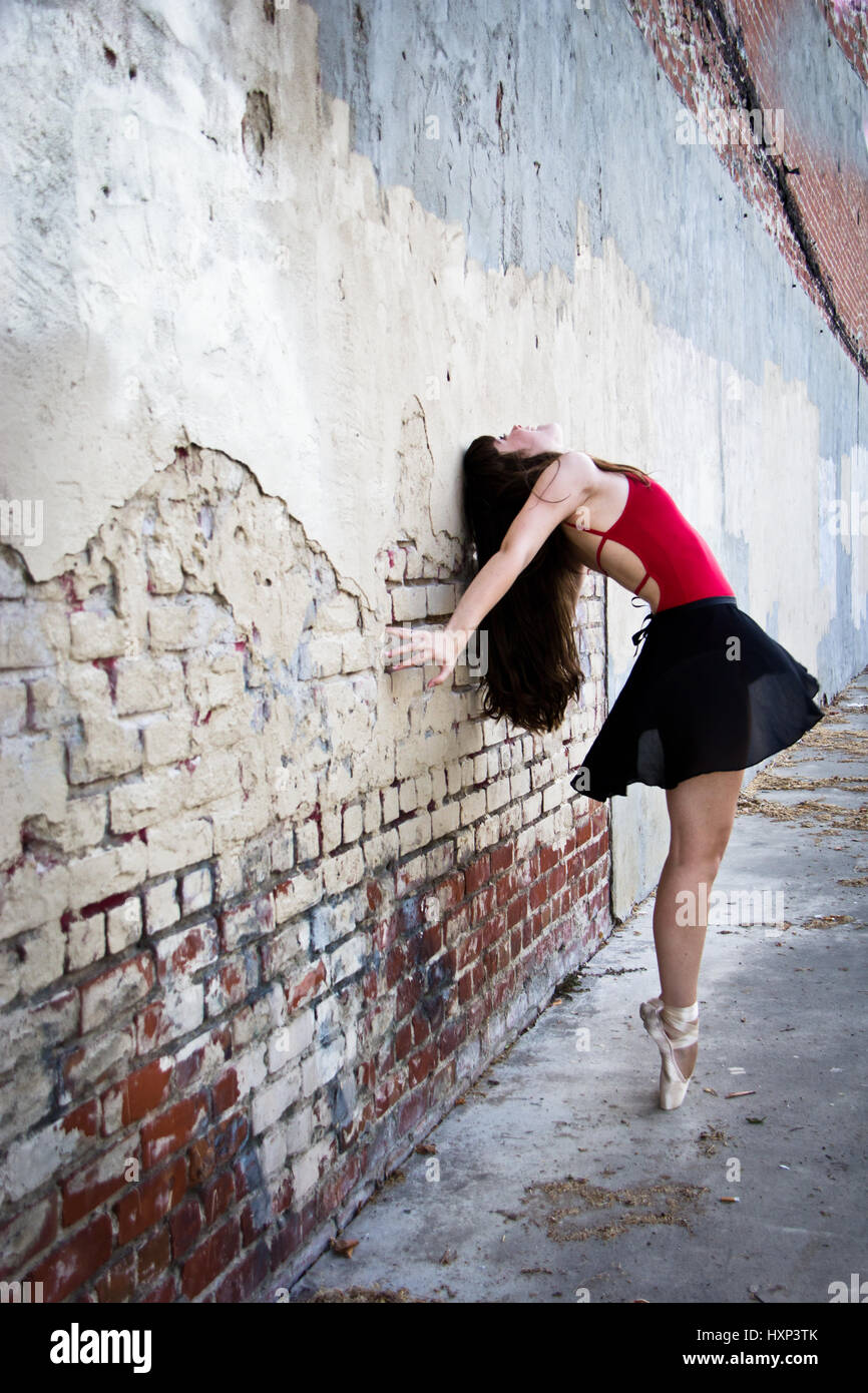 Vue latérale d'une jeune ballerine ouvrit grand les bras comme elle est jusqu'à point dans une ruelle rustique. Banque D'Images