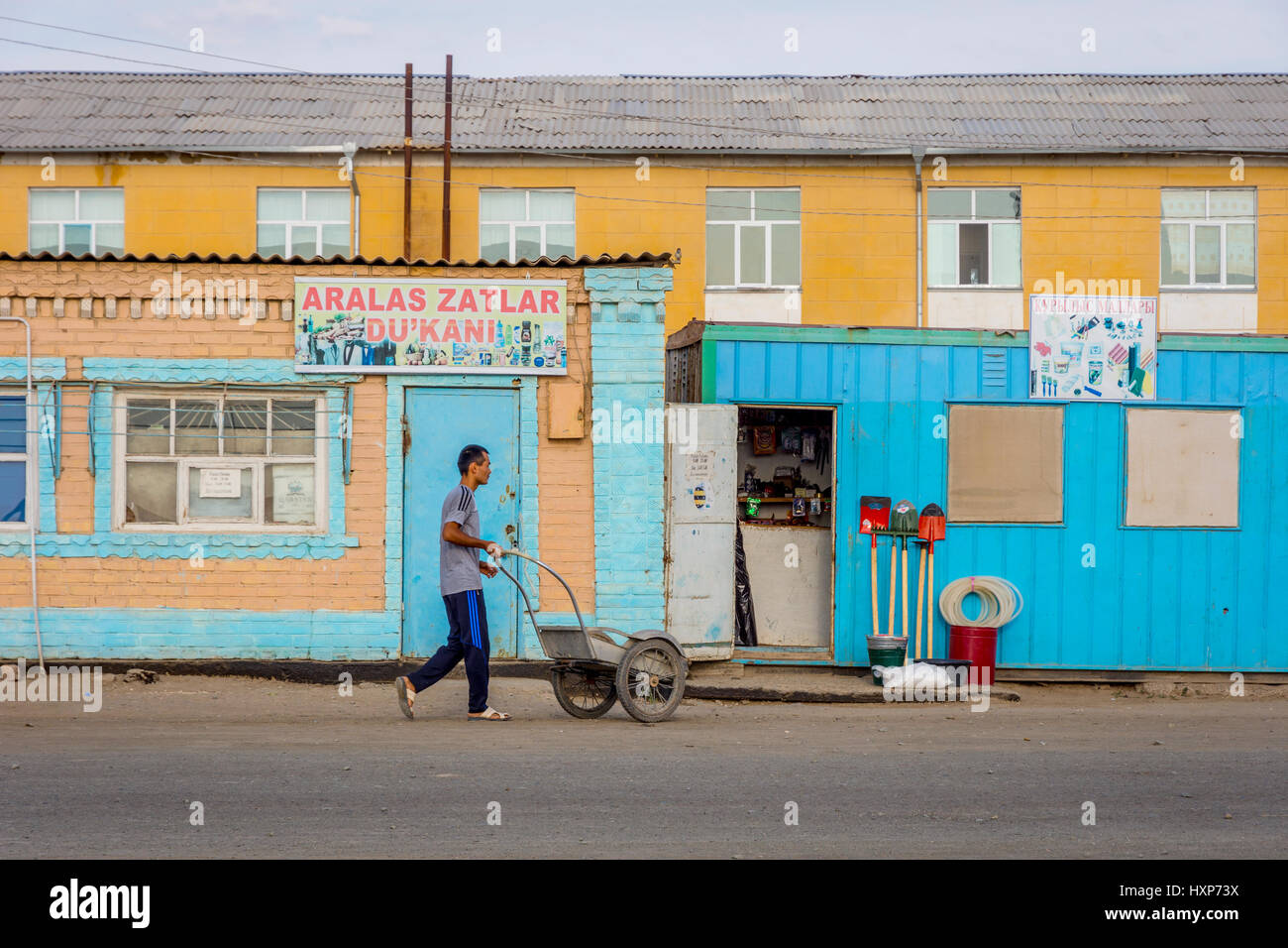 Man pushing wheelbarrow dans la rue à Muynak, Ouzbékistan Banque D'Images