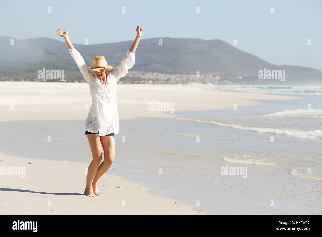 Portrait de jeune femme marchant sur la plage avec les bras levés dans la célébration Banque D'Images