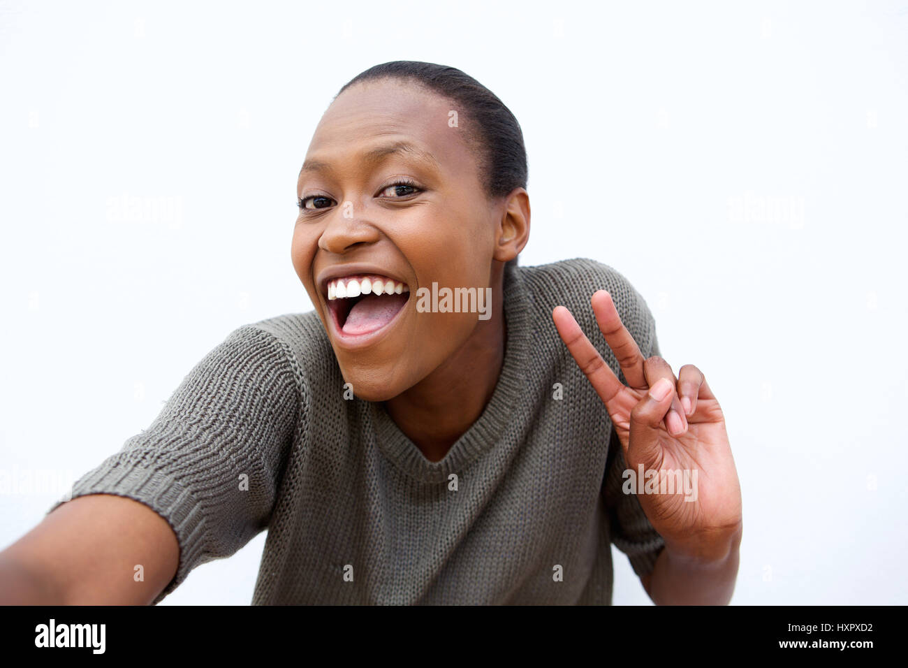 Portrait of smiling young African woman making peace sign against white background selfies Banque D'Images