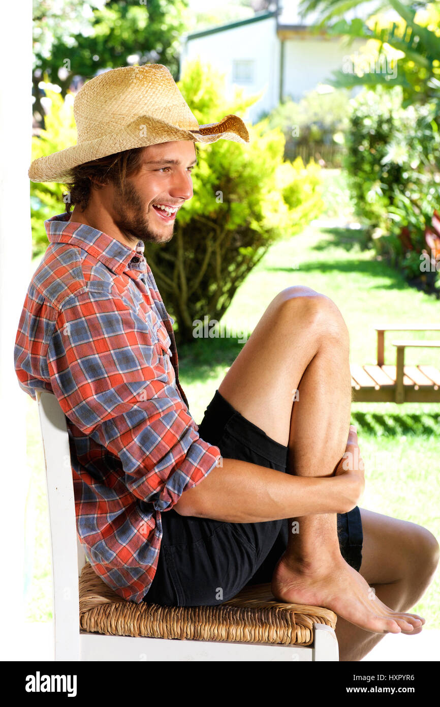 Full body portrait of smiling young man wearing cowboy hat à l'extérieur Banque D'Images