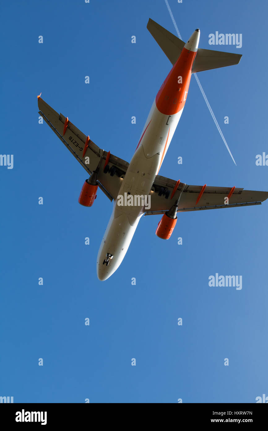 Easyjet Airbus A320 vu du dessous, tandis que l'atterrissage à Manchester. Un autre avion est en laissant une traînée de vapeur blanche au-dessus dans le ciel bleu. Banque D'Images