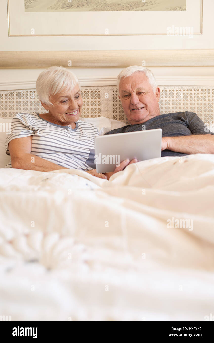 Happy senior couple using a digital tablet together in bed Banque D'Images