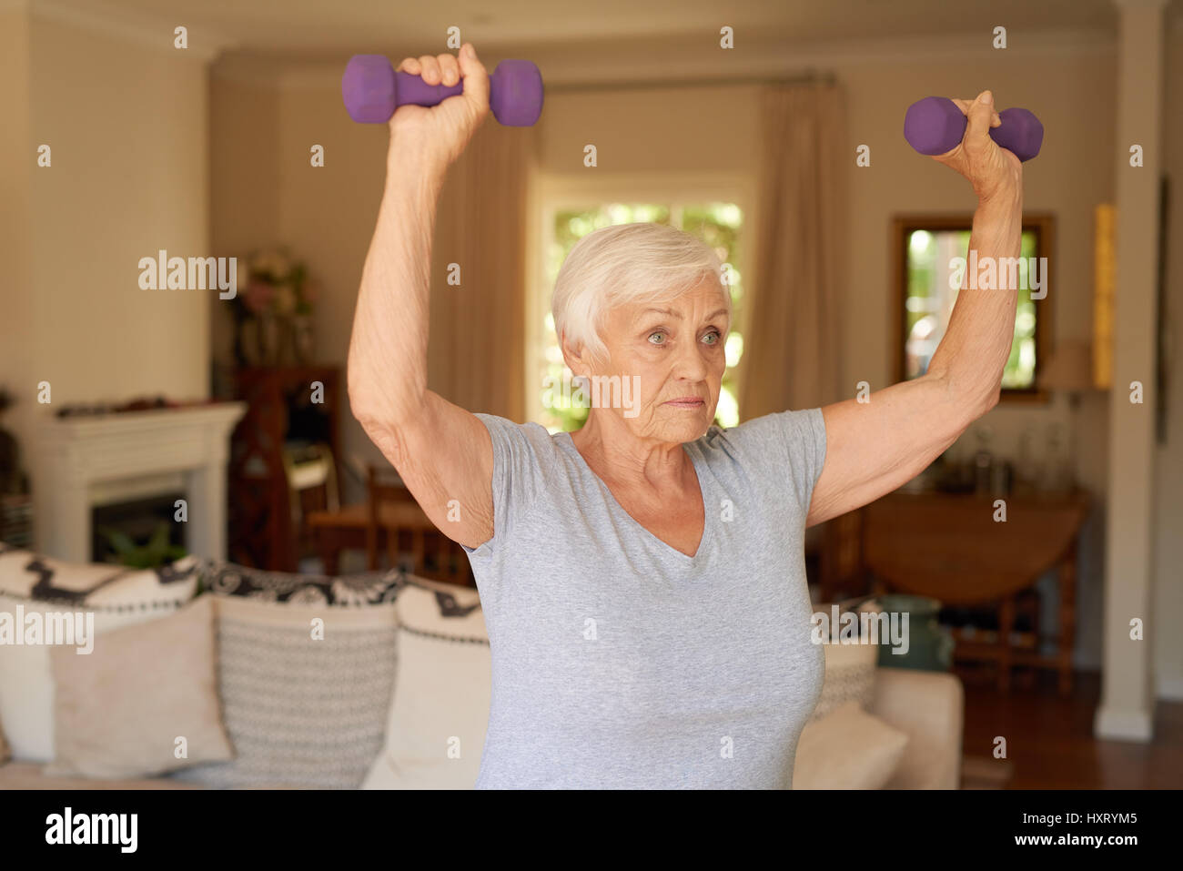 Mettre en place et active senior woman dumbells de levage à la maison Banque D'Images