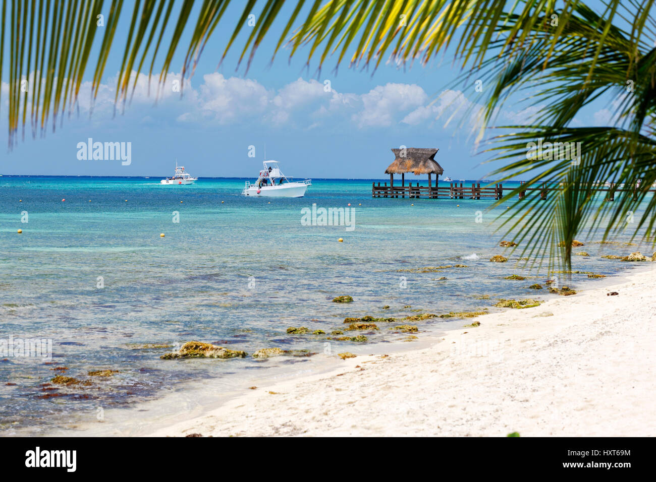 Palmiers, plage de sable fin et les bateaux de pêche près de l'embarcadère en bois Banque D'Images