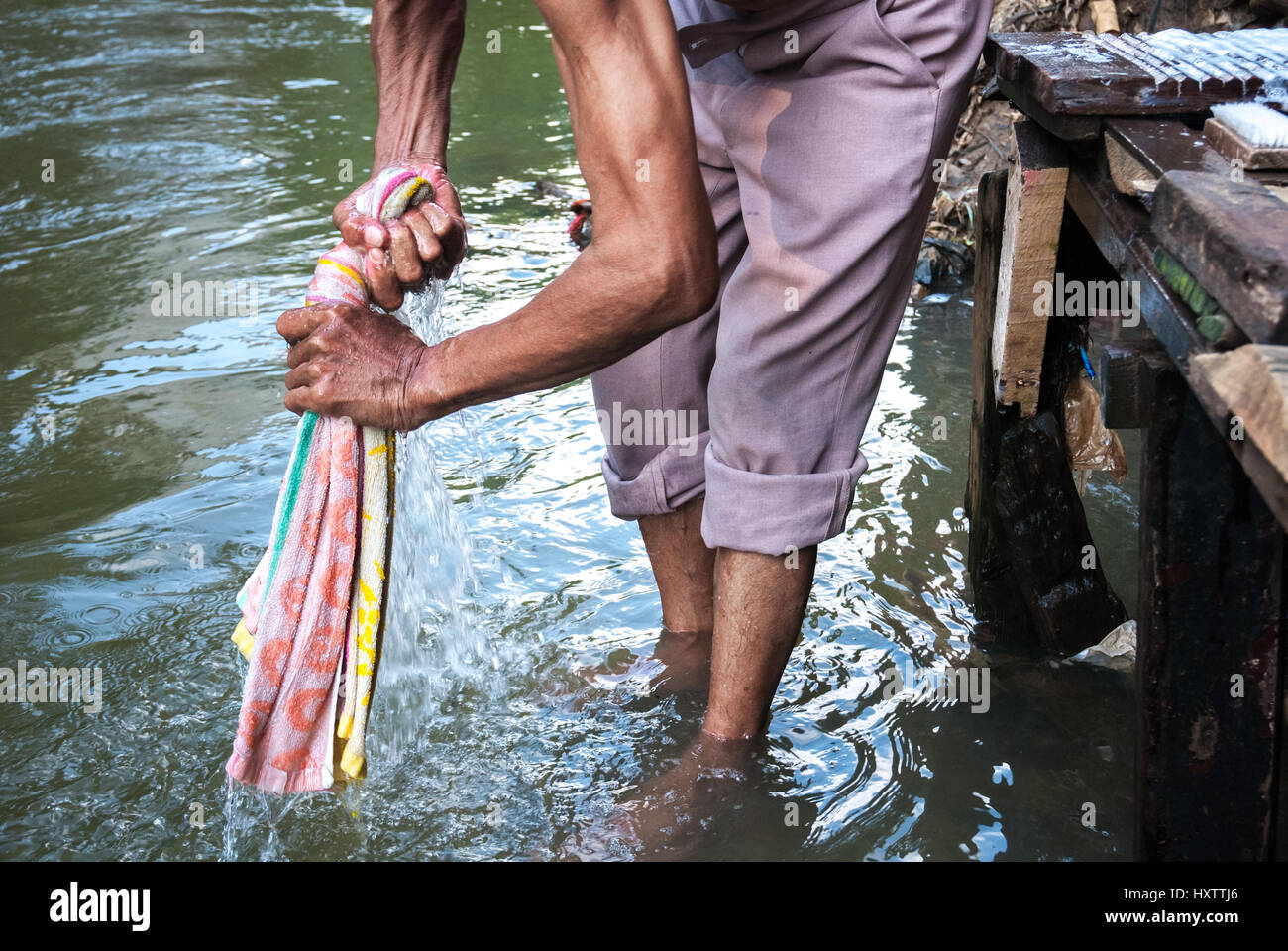 Un homme lavant une serviette dans la rivière Ciliwung, Jakarta, Indonésie. Banque D'Images