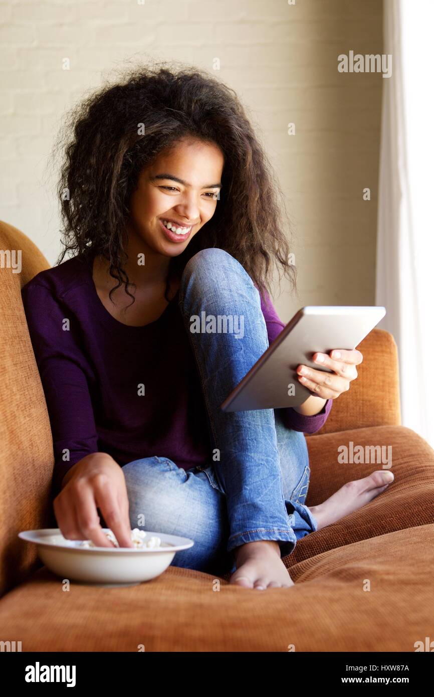 Portrait of a smiling young woman watching movie on digital tablet Banque D'Images