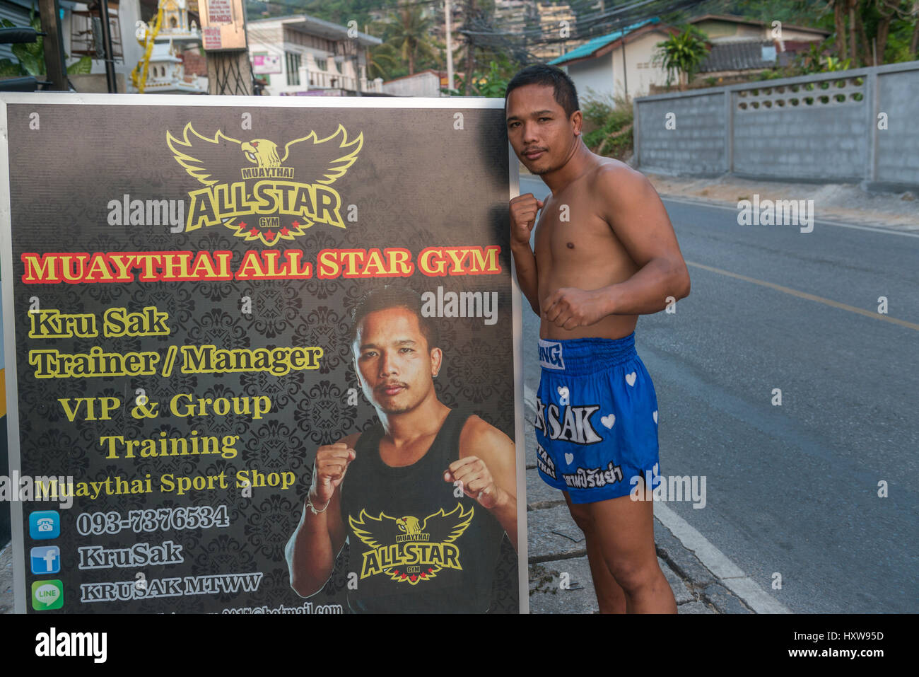 Kru Sak, un boxeur thaï ou Muay Thai, pose à côté d'un panneau d'affichage dispose de sa salle de sport à Phuket, Thaïlande. 09-Mar-2017 Banque D'Images