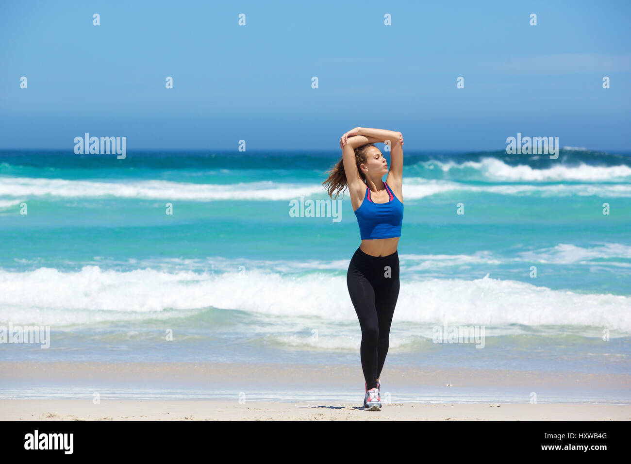 Longueur complète young woman walking on beach with arms raised Banque D'Images