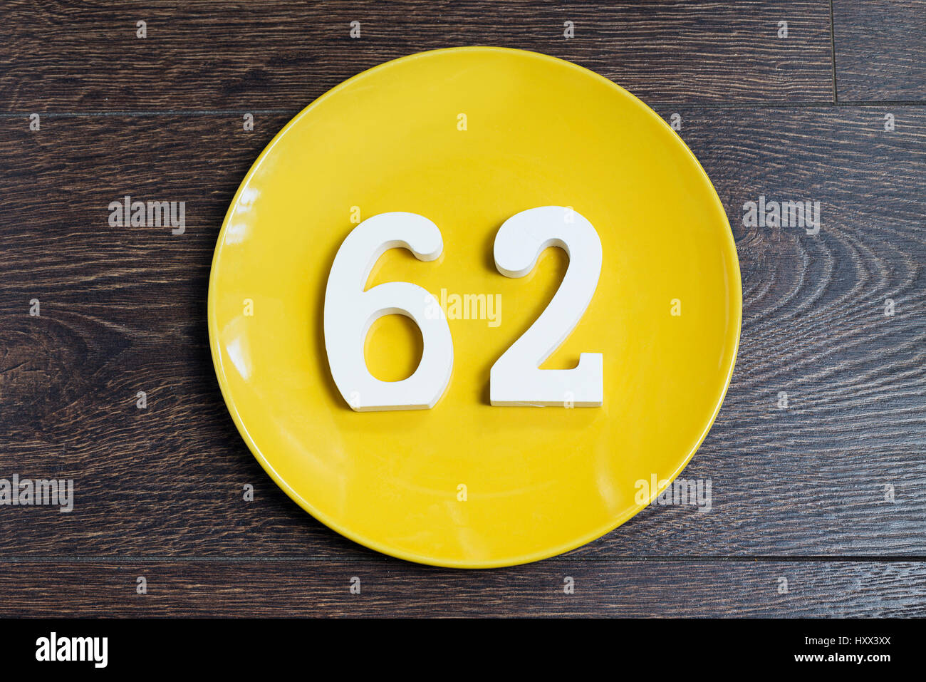 Le nombre soixante-deux sur la plaque jaune et le fond brun. Banque D'Images