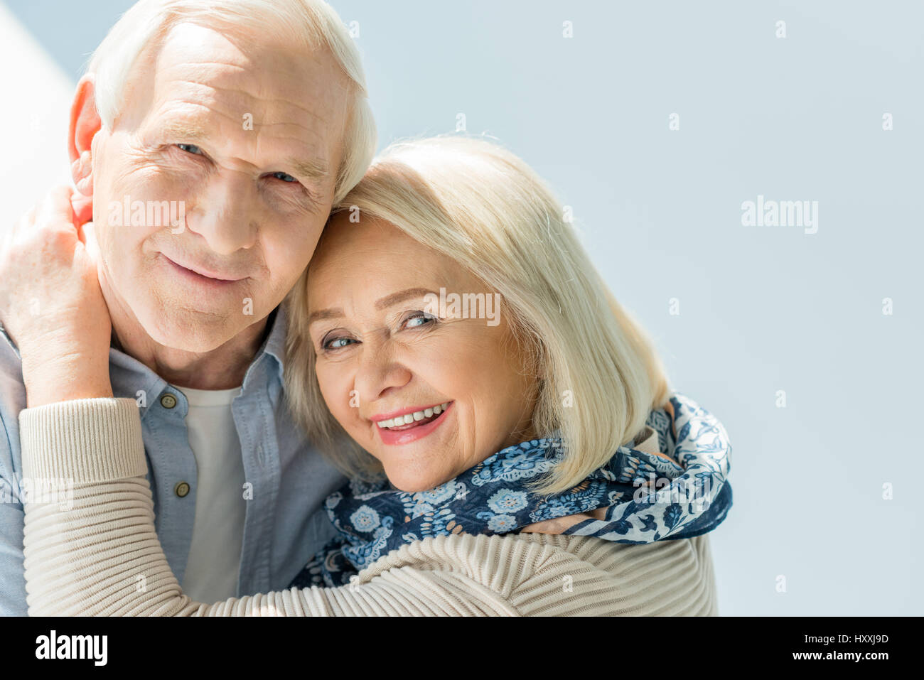 Portrait of smiling senior couple hugging on white Banque D'Images