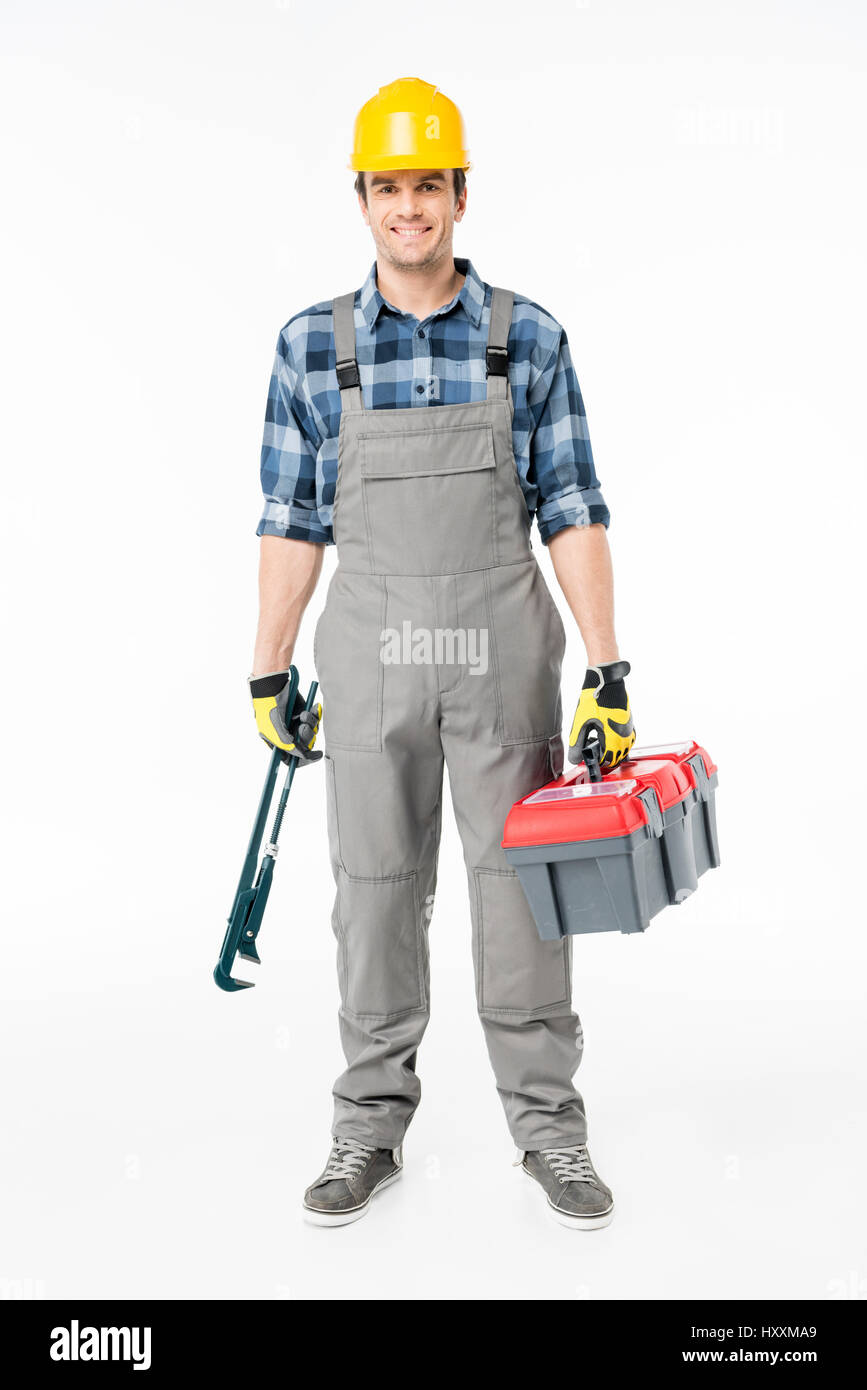 Smiling workman in hard hat holding tool kit et looking at camera on white Banque D'Images