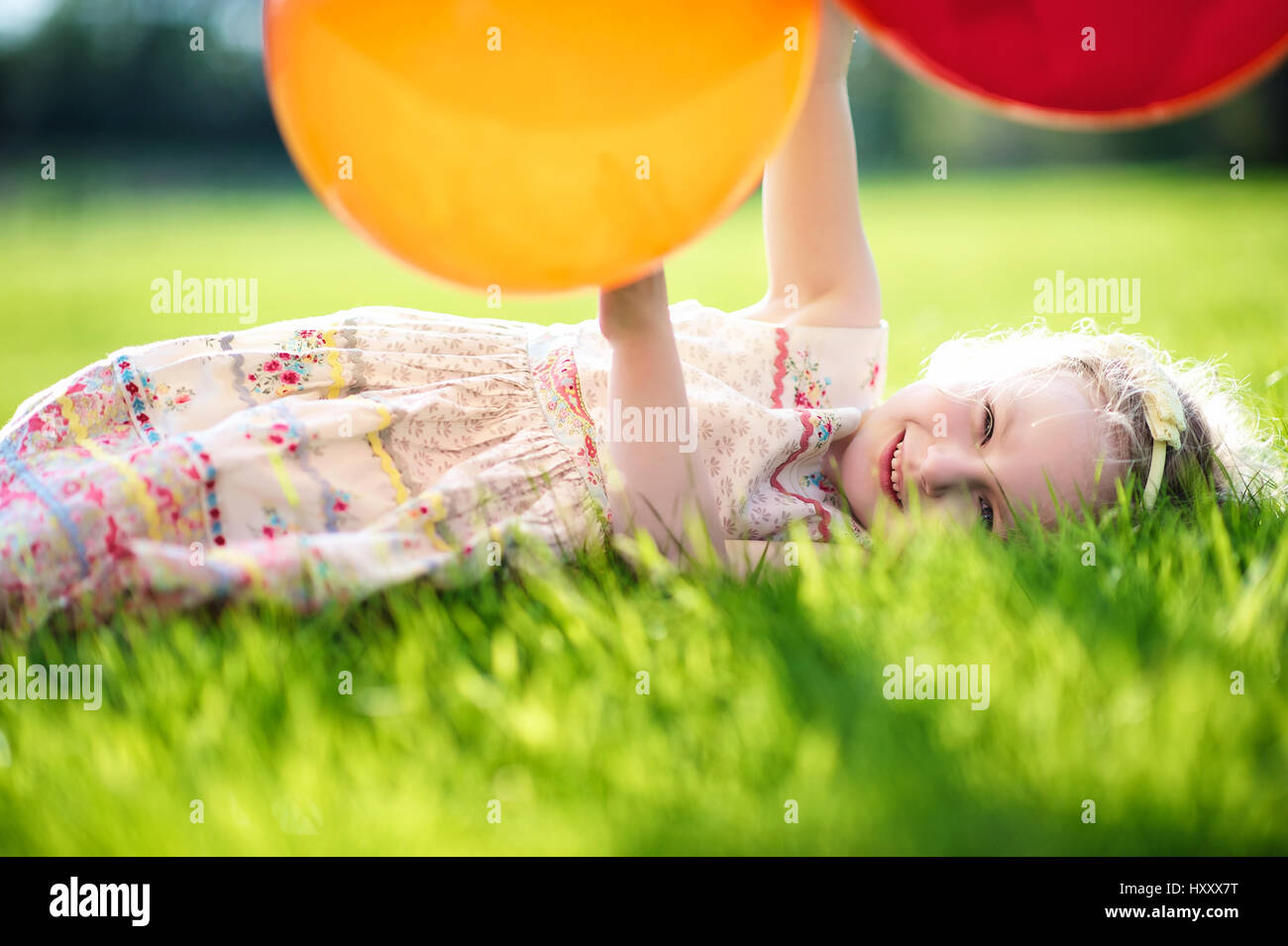 Fille blonde jouant avec bouquet de ballons dans la campagne Banque D'Images