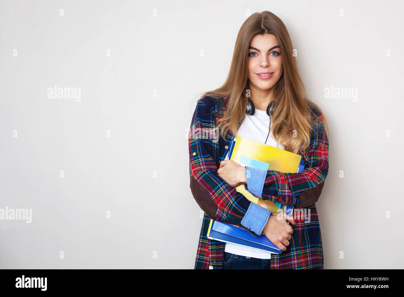 Portrait of young beautiful female student with books debout contre le mur. Banque D'Images