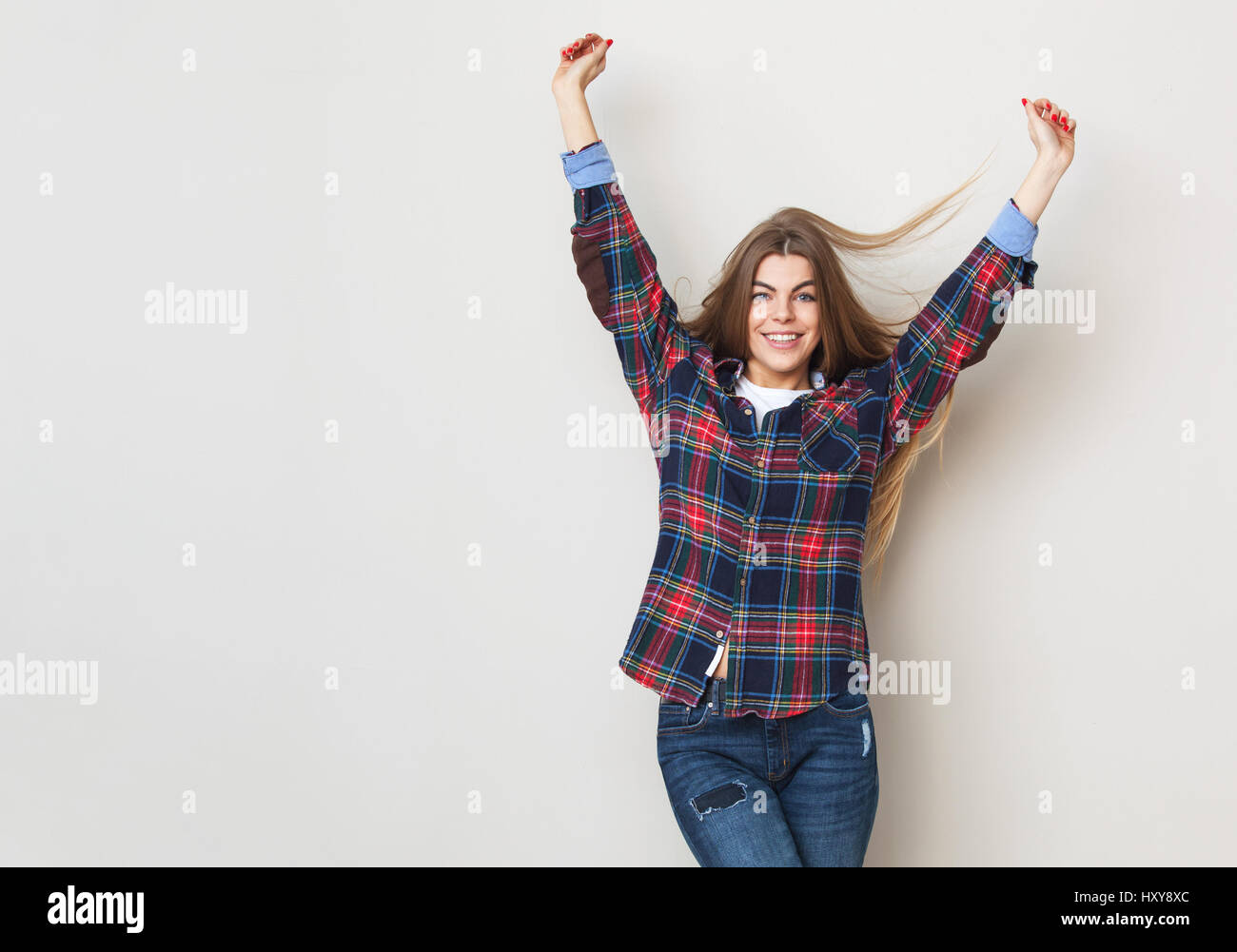 Studio portrait of happy young woman posing chemise à carreaux contre mur. Banque D'Images